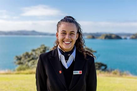 A tourism student smiles by the sea