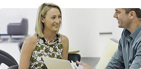 Two people talking at a desk